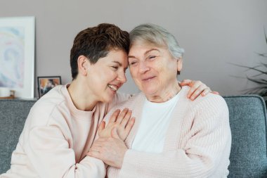 Tarafsız bir cinsiyet kadını, kıdemli annesine ya da büyükannesine sarılıyor, birlikte hassas bir anı paylaşıyor. Ebeveyn sevgisi, bakım ve nesiller boyu birlik kavramı. Anneler Günü. Mutlu aile hafta sonu birlikte eğleniyor.