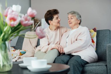 Tarafsız bir cinsiyet kadını, kıdemli annesine ya da büyükannesine sarılıyor, birlikte hassas bir anı paylaşıyor. Ebeveyn sevgisi, bakım ve nesiller boyu birlik kavramı. Anneler Günü. Mutlu aile hafta sonu birlikte eğleniyor..