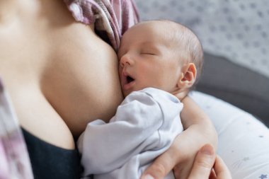 Yeni doğan bebek evde sıcak bir anne kucağında emzirdikten sonra huzur içinde uyuyor. Emziren ve kucaklayan bir anne yok. Emzirme bebek konsepti. Bebek uyumadan önce süt yiyor.