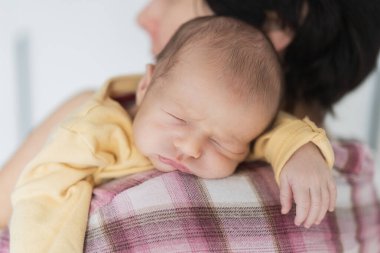 Yeni doğmuş şirin bir bebeğin portresi. Evdeki annesinin omzunda güven içinde uyuyor.