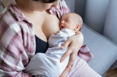 Yeni doğan bebek evde sıcak bir anne kucağında emzirdikten sonra huzur içinde uyuyor. Emziren ve kucaklayan bir anne yok. Emzirme bebek konsepti. Bebek uyumadan önce süt yiyor.
