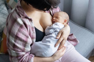 Yeni doğan bebek evde sıcak bir anne kucağında emzirdikten sonra huzur içinde uyuyor. Emziren ve kucaklayan bir anne yok. Emzirme bebek konsepti. Bebek uyumadan önce süt yiyor.