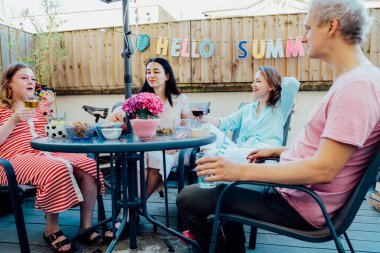 Arkadaşlar yaz tatilinde özel terasta içecekler ve atıştırmalıklarla eğleniyorlar. Arkadaşlar yemek yer, kokteyl içer, veranda partisinde birlikte eğlenir. Milenyum yaşam tarzı konsepti.