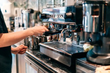 Modern bir kahve dükkanındaki otomatik makinede kahve yapan baristaya yaklaş. Küçük iş yerleri. Seçici odak