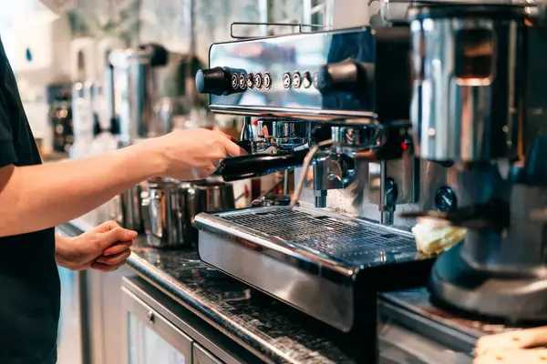 Modern bir kahve dükkanındaki otomatik makinede kahve yapan baristaya yaklaş. Küçük iş yerleri. Seçici odak