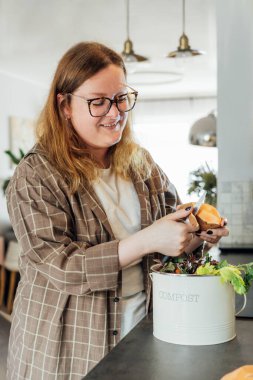 Mutfak atıklarını gübrelemek, evde geri dönüşüm yapmak. Sebzeleri kesilen artıkları çöpe atan kadın mutfak masasındaki gübre kutusu. Çevresel sorumluluk, ekoloji. Seçici odak.