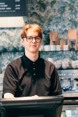 Genç garson, kafede müşteriye servis yapıyor. POS terminalinde çalışan bir adam. Kasiyer, kahveci ödeme makbuzunu kontrol ediyor. Konukseverlik, sunucu ve kahve dükkanında fişi hazırlama.