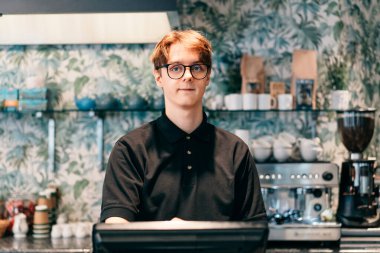 Genç garson, kafede müşteriye servis yapıyor. POS terminalinde çalışan bir adam. Kasiyer, kahveci ödeme makbuzunu kontrol ediyor. Konukseverlik, sunucu ve kahve dükkanında fişi hazırlama.