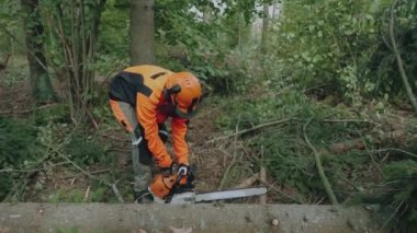 Ormandaki kadın oduncu, koruyucu ekipman uzmanı bir elektrikli testere başlatıyor, ormanların tahrip edilmesi için çok çalışıyor..