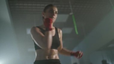 Beyaz kadın dövüşçü boks salonunda yumruklarını ve savunmalarını eğitiyor, kız hızlı saldırıyor..