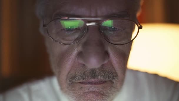 ラップトップのスクリーンを見てメガネをかけた灰色の髪の男の肖像画 コンピュータ上のニュースを読んでいる男 思考プロセス — ストック動画