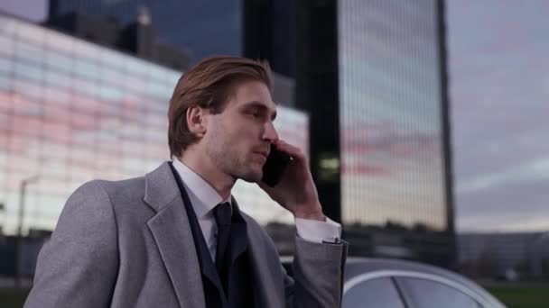 一个优雅的商人站在一辆商用车旁 用手机交谈 身穿西服的高级经理 傍晚时分 日落的画像 — 图库视频影像
