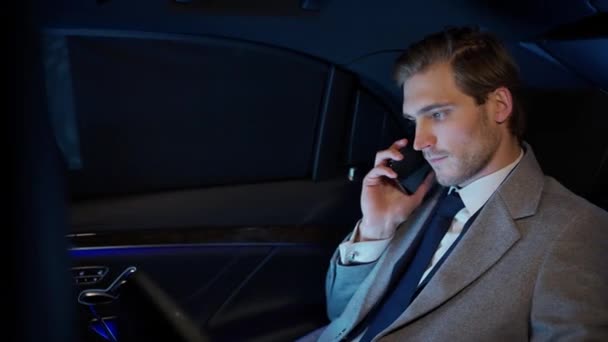 スーツのトップマネージャーは ビジネスカーの後ろに座って 携帯電話で話している 移動中の車に座って ラップトップを使用しているビジネスマン — ストック動画