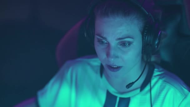 ヘッドフォンで感情的な女性ゲーマーの肖像画 ビデオゲーム サイバースポーツマンシューティング 緊張した瞬間にチームとコミュニケーション — ストック動画
