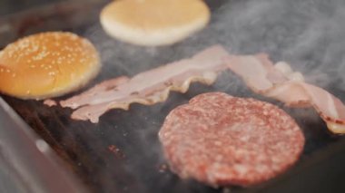 Barbekü, ızgarada hamburger pişirme süreci, et, domuz pastırması ve çörek ızgarada kızartılıyor, 4K süper yavaş çekim..