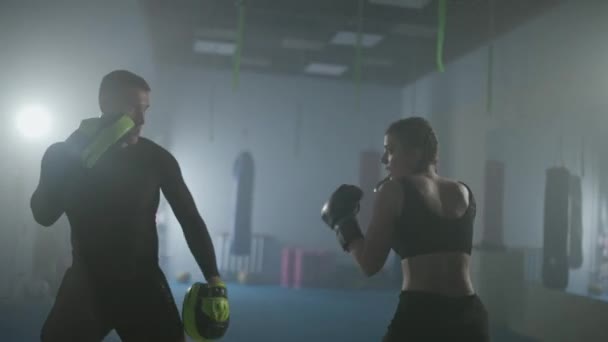 女性戦闘機は 彼のファストパンチを訓練 パンチフォーカスミット ボクシングジムのコーチとトレーニング日 若い女性は速くストライキ — ストック動画