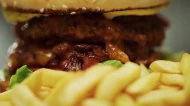 Abur cubur, pişmiş hamburger ve patates kızartması manzarası, etli duble burger pişirme süreci, 4k süper ağır çekim..