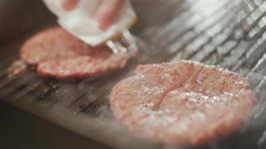 Sokak yemekleri, hamburger pişirme süreci, ızgarada kızartılmış et pirzolası, şef yemek festivalinde aşçılık yapıyor, 4k süper yavaş çekim..