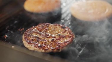 Sokak yemekleri, ızgarada hamburger pişirme süreci et ve çörek ızgarada kızartılır, hamburgerler, 4K süper yavaş çekim..