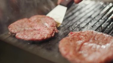 Sokak yemekleri, hamburger pişirme süreci, ızgarada kızartılmış et pirzolası, şef yemek festivalinde aşçılık yapıyor, 4k süper yavaş çekim..