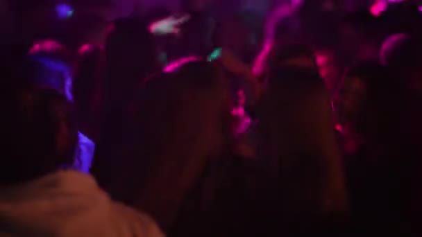 白俄罗斯 明斯克 2022年11月19日 年轻人在俱乐部的一个晚会上 在一个五彩缤纷的灯光下 在人群中嬉戏跳舞 — 图库视频影像