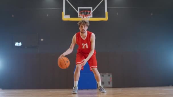 运动生活方式 篮球运动员在地板上击球 赛前热身 高加索运动员看着镜头 室内游乐场 — 图库视频影像