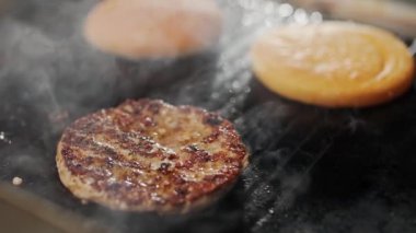 Sokak yemekleri, ızgarada hamburger pişirme süreci et ve çörek ızgarada kızartılır, hamburgerler, 4K süper yavaş çekim..