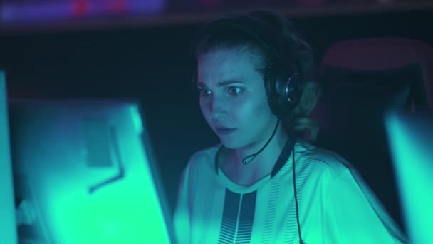一个情绪激动的女游戏玩家在耳机中的形象 玩电子游戏 年轻的女网络运动员在紧张的时刻大叫并与团队交流 — 图库视频影像