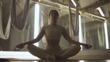 Genç kadın yoga yapıyor ve meditasyon yapıyor, sakin bir ruh hali içinde, beyaz kadın yerde oturuyor..