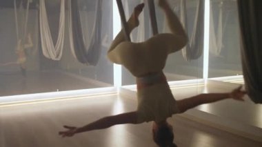 Aynalı odada yoga yapan kadın, esnek kadın yoga elementleriyle güzel bir dans eder, kumaş iplerle odada dans eder..