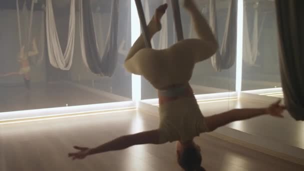 女人在镜室里做瑜伽 柔韧的女人用瑜伽元素表演美丽的舞蹈 用布绳在房间里伸展舞蹈 — 图库视频影像