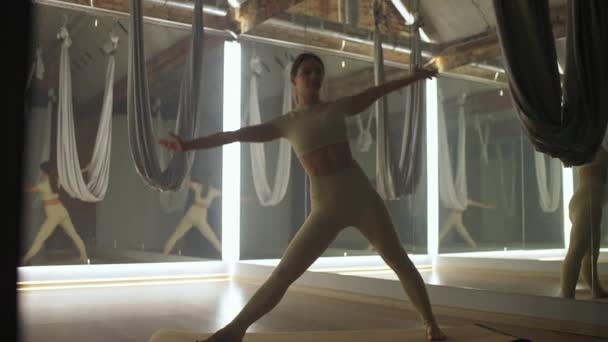 年轻的女人在一个有镜子的房间里做瑜伽 而女人在一个有瑜伽元素和反射的房间里做伸展运动 — 图库视频影像