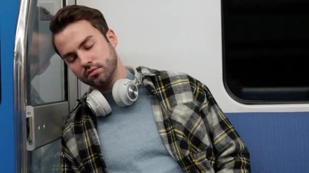 地下鉄に乗っている間寝ている若い疲れた男 公共交通機関の学生 疲れた男は家に帰る — ストック動画