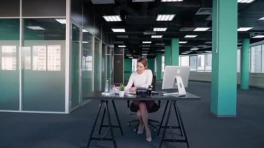Fazla mesai yapıyor, genç iş kadını ofiste bir masada oturuyor ve bir bilgisayar üzerinde çalışıyor, yönetici finansal belgeler üzerinde çalışıyor, işine odaklanmış bir yönetici..