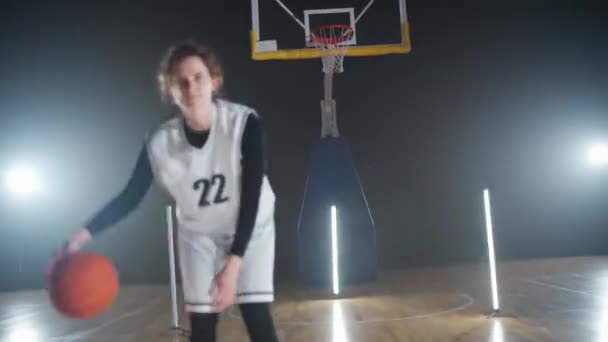 职业女篮手的形象在赛前把球打出地板 职业篮球手看着镜头 室内操场 — 图库视频影像
