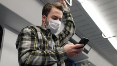 Tıbbi maskeli genç adam metroya biniyor, akıllı telefon kullanıyor ve internette sörf yapıyor, bir öğrenci üniversiteye okumaya gidiyor, sabah toplu taşıma aracıyla..