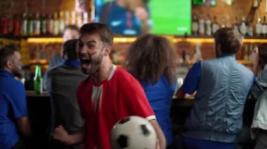 Farklı ırkların futbol taraftarları bira içer ve barda futbol maçı izler, karşı takımın taraftarı bir futbol maçında gol atmaktan zevk alır ve zafere sevinir, komik bir andır..