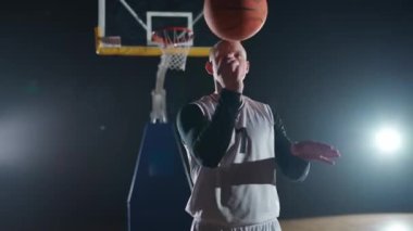 Basketbolcu parmağında dönen bir topla kameraya bakarak bir numara gösteriyor..