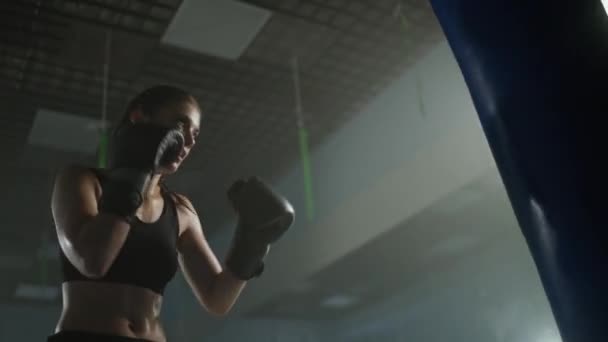 电影灯光下 女战士打拳袋 训练他的拳 在拳击馆训练一天 女人的力量 — 图库视频影像