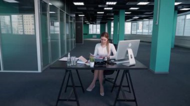 Fazla mesai yapıyor, genç iş kadını ofiste bir masada oturuyor ve bir bilgisayar üzerinde çalışıyor, yönetici finansal belgeler üzerinde çalışıyor, işine odaklanmış bir yönetici..