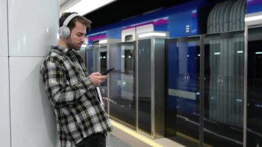 Genç adam metroda tren bekliyor, akıllı telefon kullanıyor ve kablosuz kulaklıkla müzik dinliyor, bir öğrenci üniversiteye okumaya gidiyor, toplu taşıma araçlarıyla..