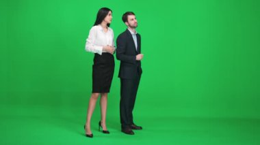 Takım elbiseli bir çift genç adam ve kadın krom anahtarın yeşil alanında durup basit şeyleri izleyip tartışıyorlar, kromakey şablonu.