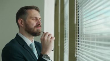 Düşünme süreci, takım elbiseli odaklı iş adamı ofisin panoramik penceresinde duruyor ve düşünce süreci, doğal ışıklandırma.