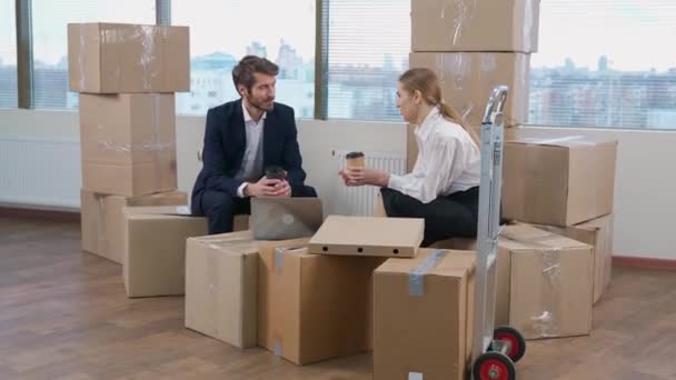 搬到一个新的办公室 男人和女人坐在纸板箱上 交流和喝咖啡 公司的搬迁 — 图库视频影像