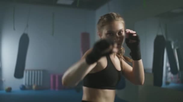 スローモーション 女性戦闘機は彼のパンチを訓練し ボクシングジムでトレーニング 女性の列車一連のパンチ 女性のパワー — ストック動画