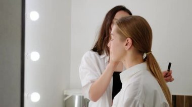 Cilt tonlama işlemi, kadın makyaj sanatçısı haberlerden önce bir TV sunucusu uyduruyor, medya etkinliğine hazırlanıyor, makyaj sanatçısı iş başında..