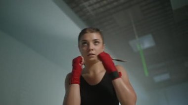 Kadın gücü, genç kadın boksör yumruklarını eğitiyor, boks salonunda antrenman yapıyor, kadın yumrukları seri olarak eğitiyor..