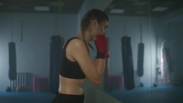 女性のパワー 慎重な女性戦闘機は ボクシングジムで彼のパンチと防衛を訓練し 鏡の前にボクサー列車 — ストック動画