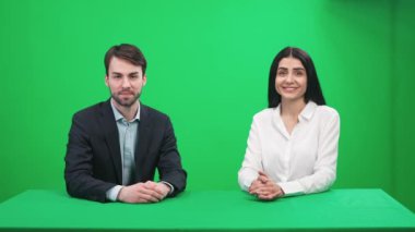 Haber muhabirleri stüdyoda oturur ve kameraya bakar, yeşil arka planda bir haber programı sunar, TV haber ajansları için bir şablon, iş yerinde gazeteciler, kromakey.