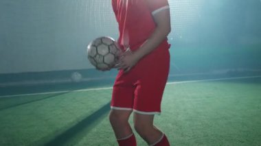 Genç futbolcu bir futbol topuyla oyunlar oynuyor, bir futbol topunu fırlatıyor ve dengeliyor..